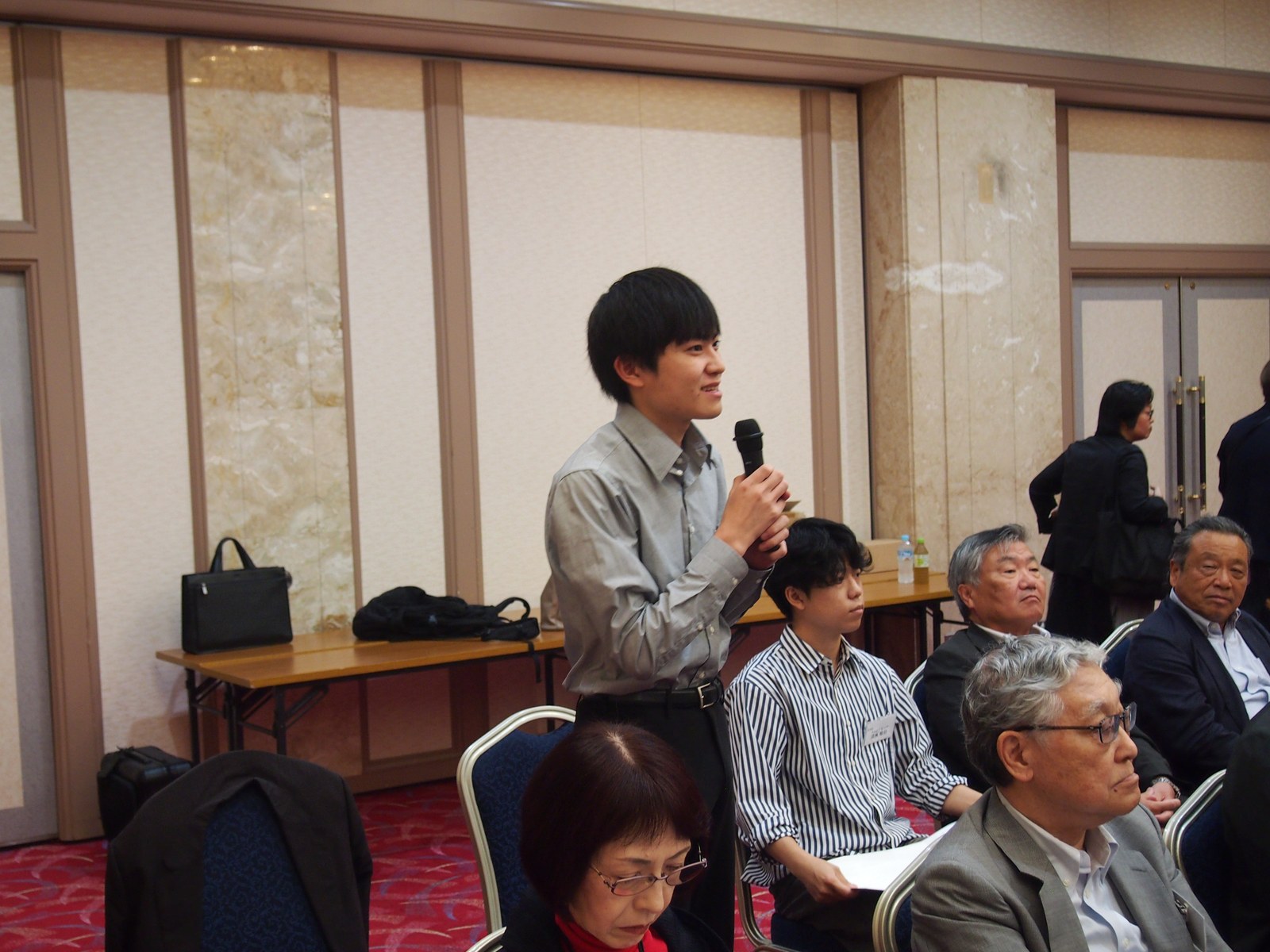 第7回交流会の会場でマイクを持って発言する参加者